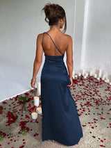 Woman in a navy blue one-shoulder satin gown with a high slit, seen from the back.