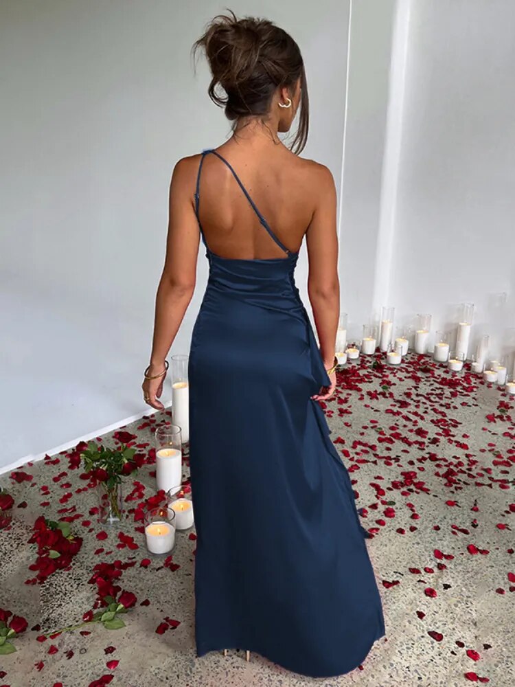Woman in a navy blue one-shoulder satin gown with a high slit, seen from the back.