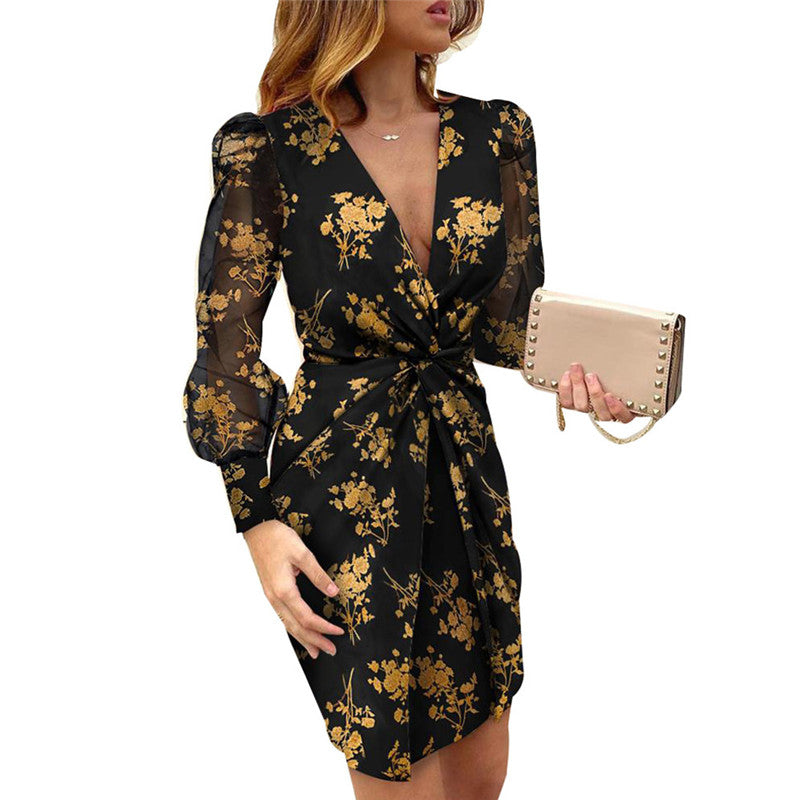 Woman wearing a black dress with a gold floral print and sheer sleeves.