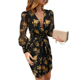 Woman wearing a black dress with a gold floral print and sheer sleeves.