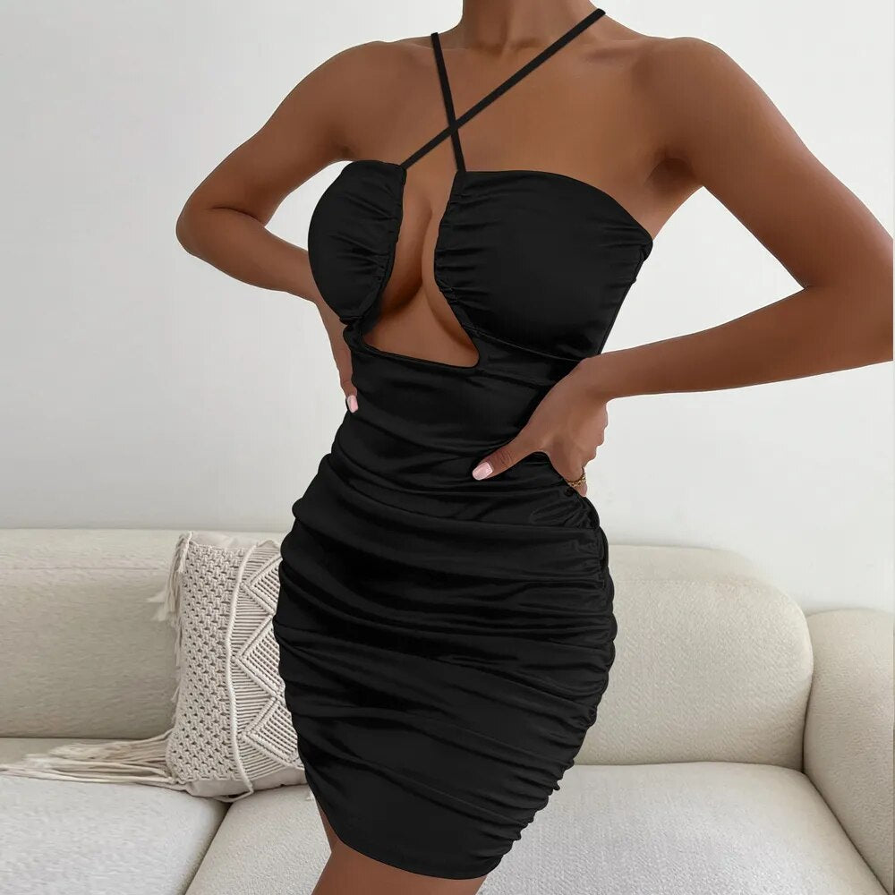 Woman with hands on hips wearing a black halter neck mini dress with a cut-out detail and ruching.