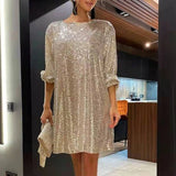 Woman wearing a short, gold sequined dress with 3/4 sleeves and a matching clutch.