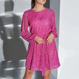Woman wearing a pink sequined dress with long, puffed sleeves and a belted waist.