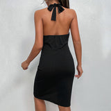Back view of a woman wearing a black halter neck mini dress with a deep V-neck and ruched detailing on the front.