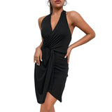 Woman wearing a black halter neck mini dress with a deep V-neck and ruched detailing on the front.