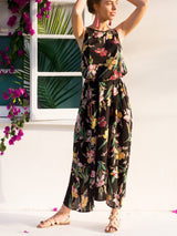Woman in a black floral maxi dress with her hands on her head, looking to the side.