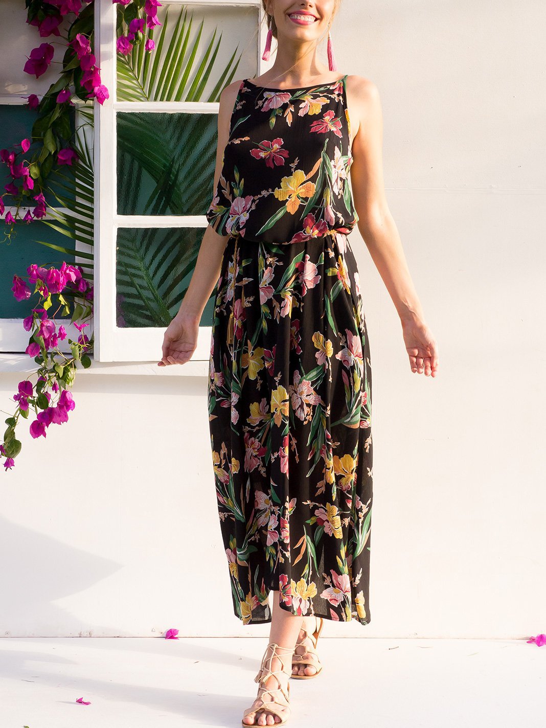 Woman in a black floral maxi dress smiling and looking forward.