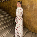 Woman from behind wearing a white polka dot maxi dress with red polka dots and bell sleeves.