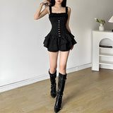 Woman wearing a black pinstripe corset-style dress with ruffled hem and black knee-high boots.