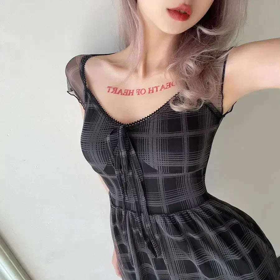 Full body shot of a woman in a black and gray plaid dress.