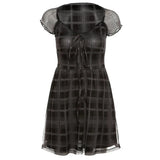 A black and gray plaid dress with sheer sleeves and a tie-front closure, displayed on a white background.