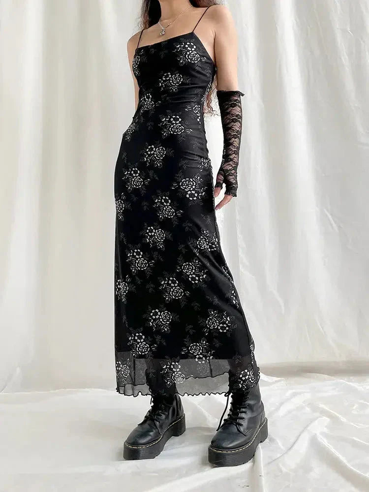 Full-body shot of a woman in a black floral slip dress, lace gloves, and platform boots.
