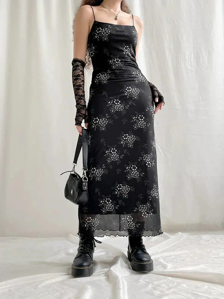 A woman poses in a black floral slip dress, lace gloves, and platform boots, with a black shoulder bag.
