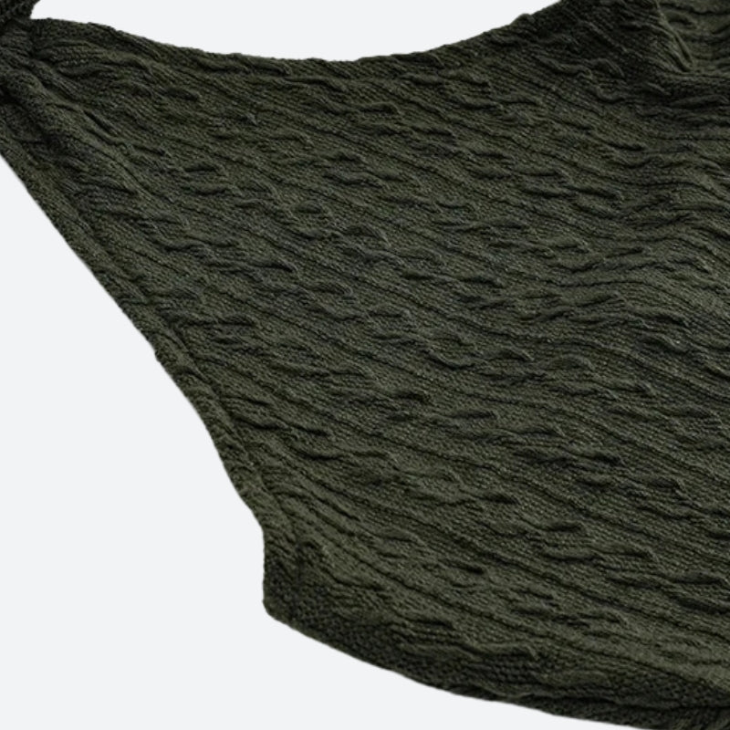 Close-up of the textured fabric and hem of an olive green dress