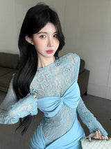 Close-up of a woman's face and upper body in a light blue lace dress with a ruched skirt and a bow detail on the bust.