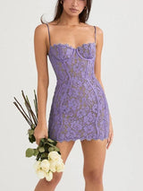 Woman wearing a lavender lace mini dress with spaghetti straps and a sweetheart neckline, holding a bouquet of white roses.
