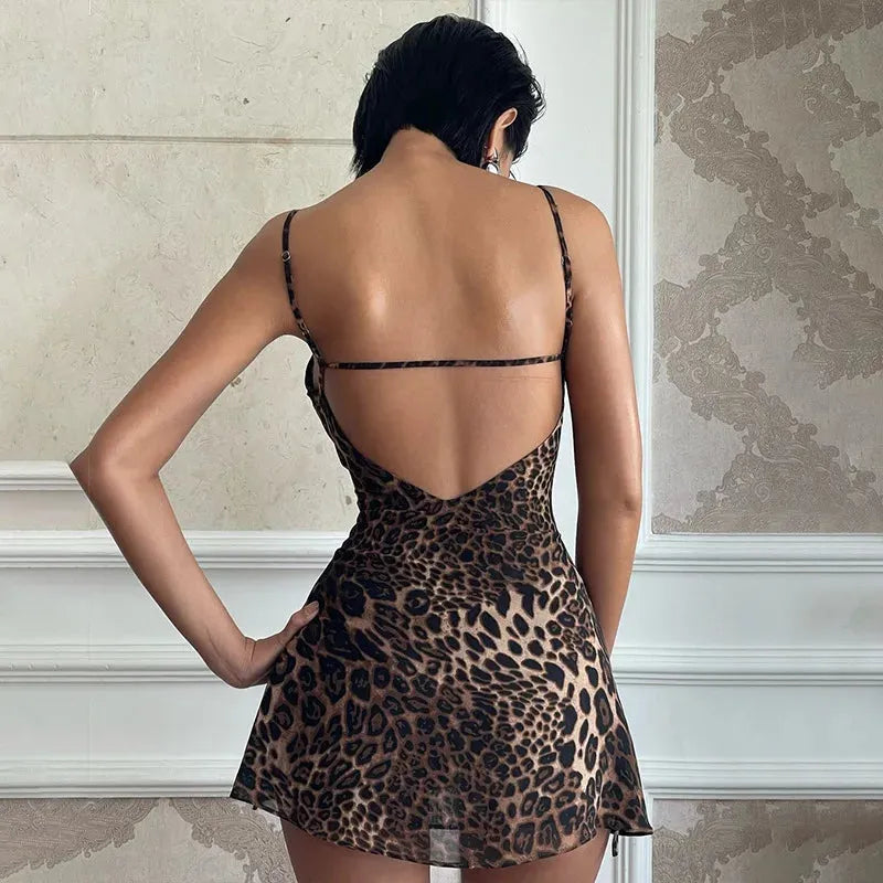 Woman wearing a short leopard print slip dress with spaghetti straps, back view showing open back detail.