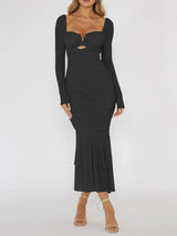 Woman wearing a black ruched midi dress with sheer long sleeves and a ruffled hem