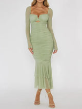 Woman wearing a green ruched midi dress with sheer long sleeves and a cutout detail