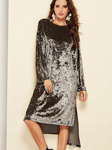 A woman modeling a crushed velvet dress in a darker, more muted tone, with a round neckline and long sleeves.