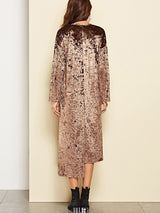 Back view of a woman wearing a crushed velvet brown dress with long sleeves and a high-low hemline, paired with black boots.