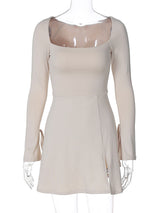 An ivory long-sleeved mini dress with a square neckline, tie details on the sleeves, and a thigh-high slit is displayed on a mannequin.