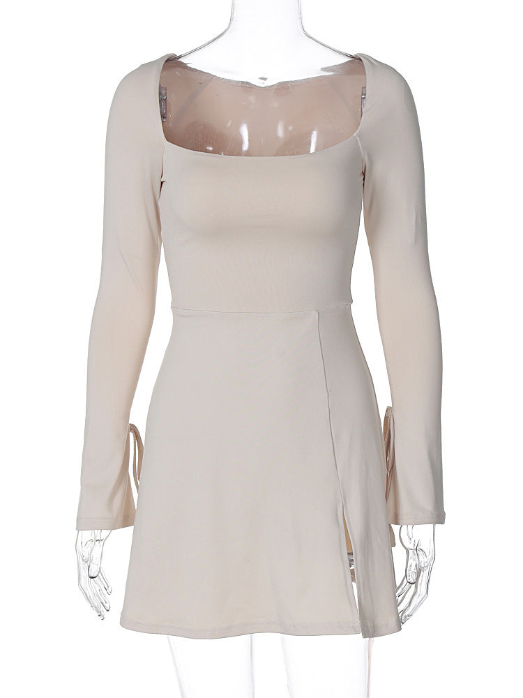 An ivory long-sleeved mini dress with a square neckline, tie details on the sleeves, and a thigh-high slit is displayed on a mannequin.