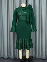 A green sequined dress with a bow detail displayed on a mannequin.