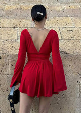 Back view of a woman in a red mini dress with flared sleeves and a deep V-neck.