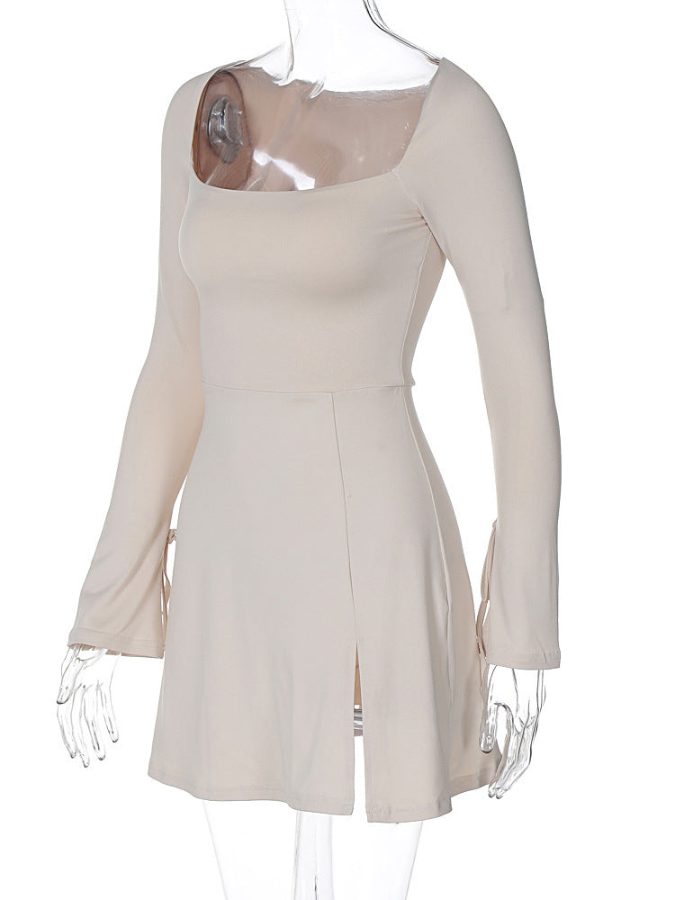 An ivory long-sleeved mini dress with a square neckline, tie details on the sleeves, and a thigh-high slit is displayed on a mannequin.