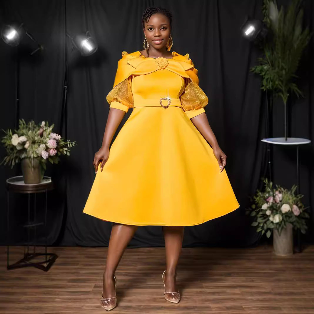 A woman stands in a bright yellow dress with puffed sleeves and a matching belt.