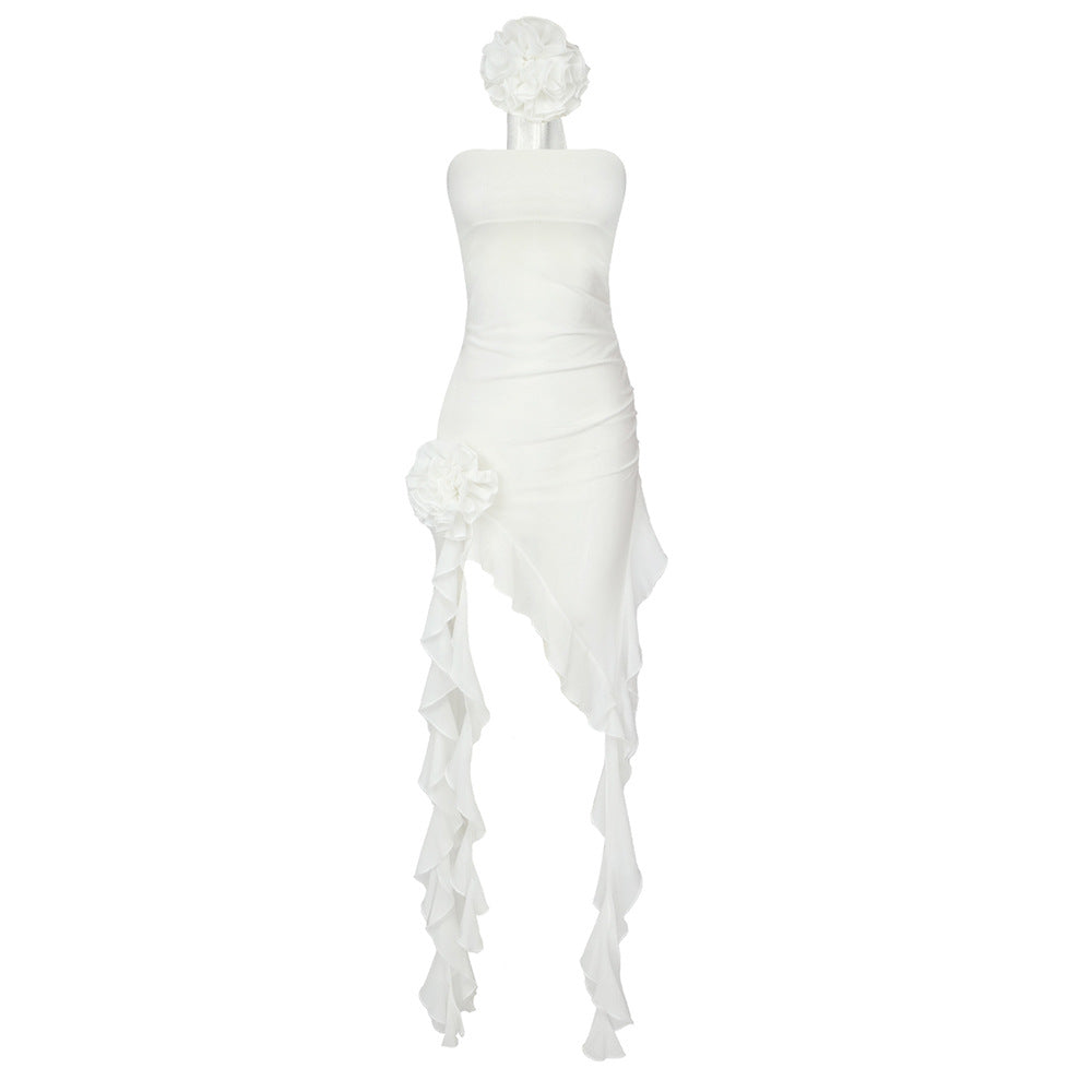 A white strapless dress with ruffled detailing and a flower embellishment is shown on a white background.