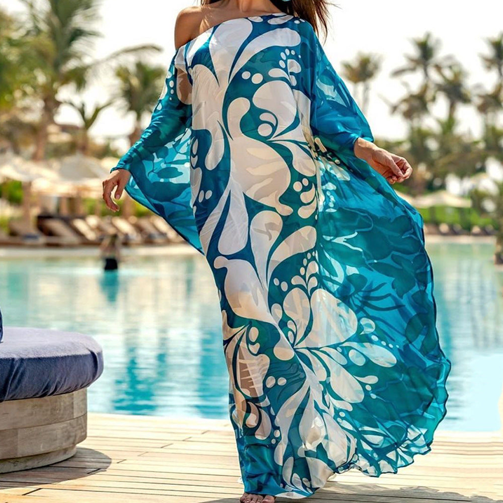 Woman in a flowing blue and white patterned kaftan with arms outstretched by a pool