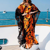 Woman wearing a vibrant orange and black patterned kaftan on a yacht