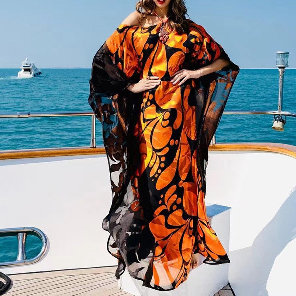 Woman wearing a vibrant orange and black patterned kaftan on a yacht