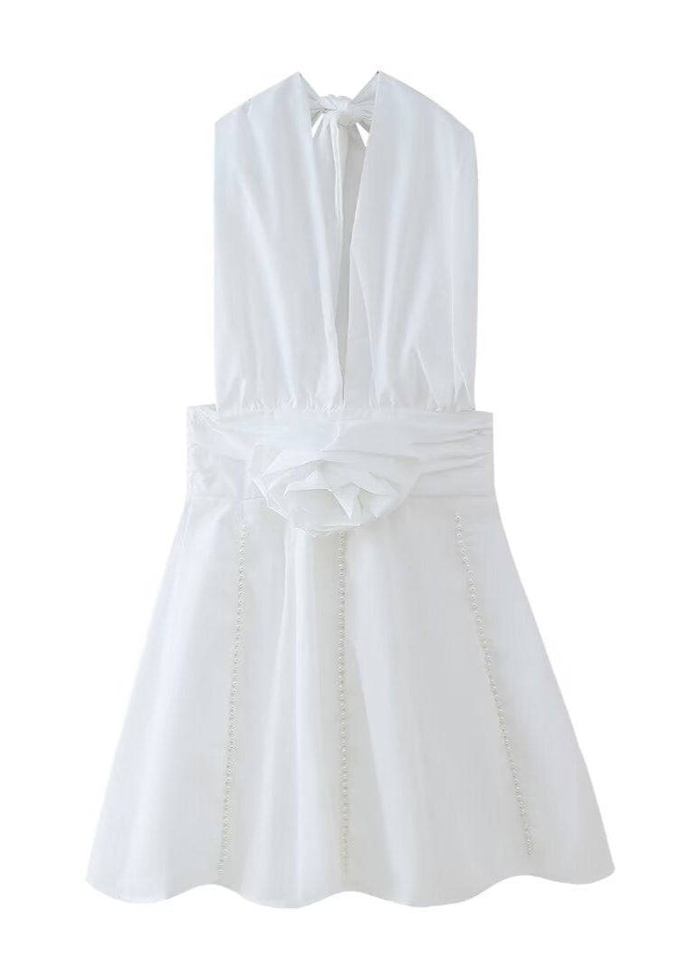 A white halter neck dress with a deep V-neckline, rose embellishment, and pearl trim, displayed on a white background.