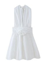 A white halter neck dress with a deep V-neckline, rose embellishment, and pearl trim, displayed on a white background.