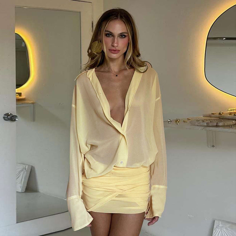A woman wearing a pale yellow sheer ruched dress with a plunging neckline and long sleeves.