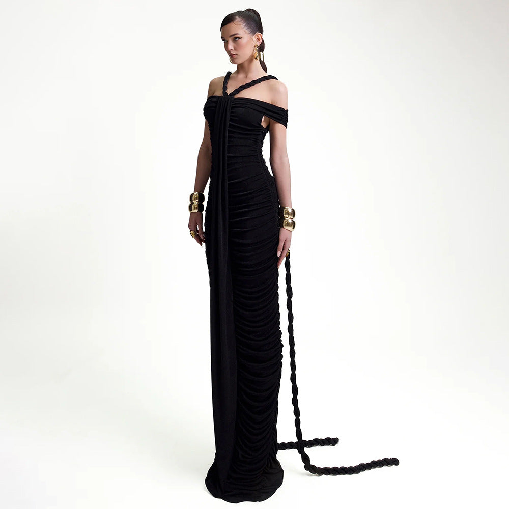 Full-length shot of a model in a black ruched gown with a train, showcasing the off-the-shoulder design and halter neckline.