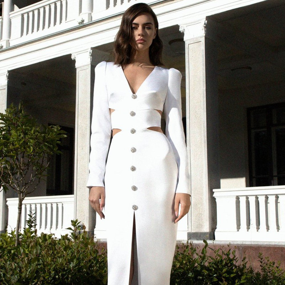 Woman wearing a white midi dress with cut-outs and a high slit, standing in front of a white building.