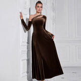 woman in a brown velvet one-shoulder dress standing next to a white wall
