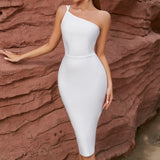 Close-up of a woman in a white one-shoulder bandage dress against a rock formation.
