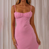 Close-up of the ruched bust and spaghetti straps of a pink slip dress.