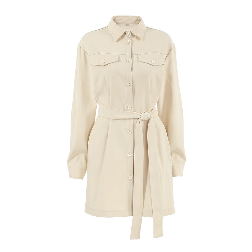 A long-sleeved beige shirt dress with a belted waist and chest pockets, displayed against a white background.