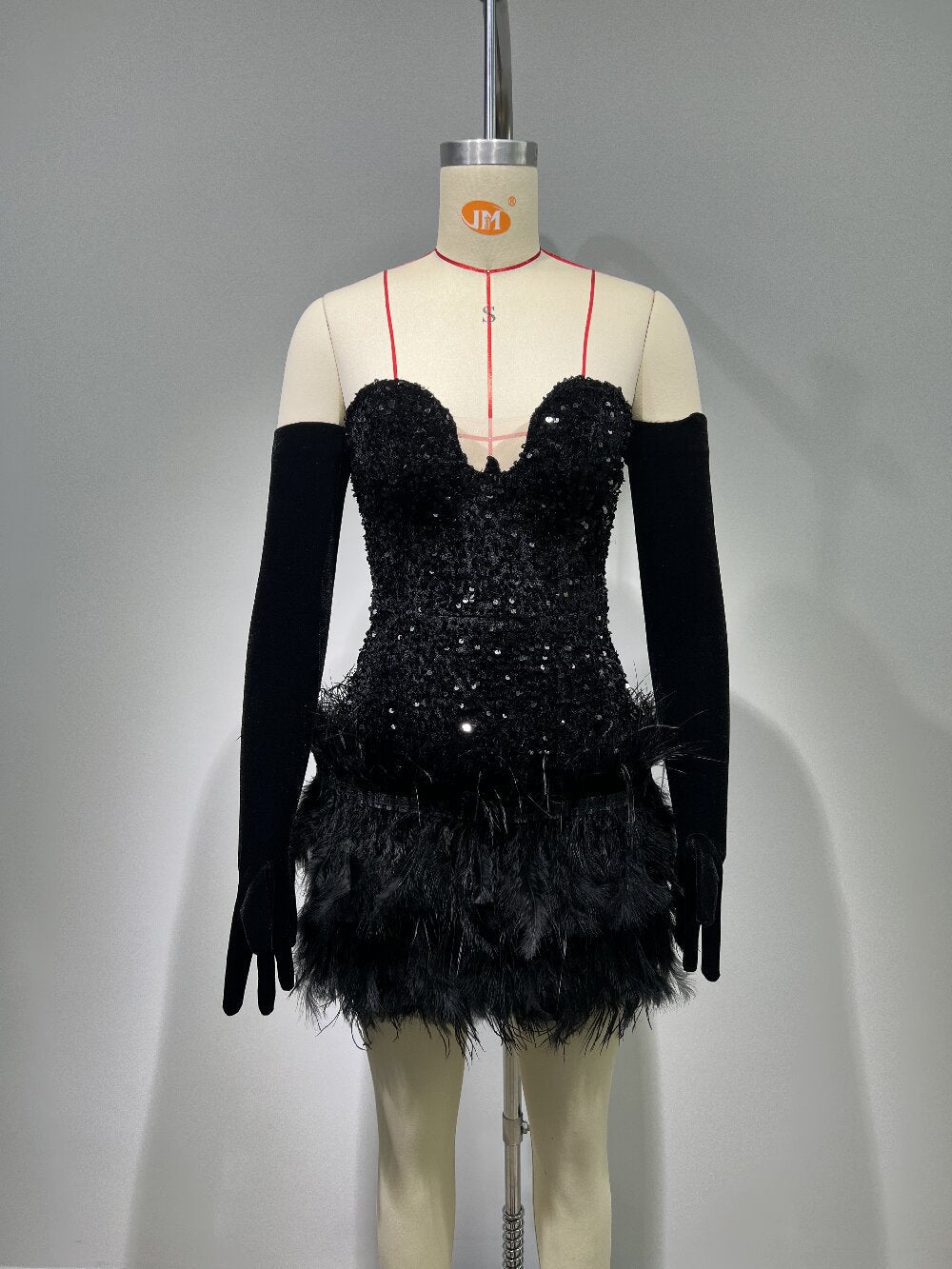 A black sequined and feathered mini dress with long black gloves displayed on a mannequin.