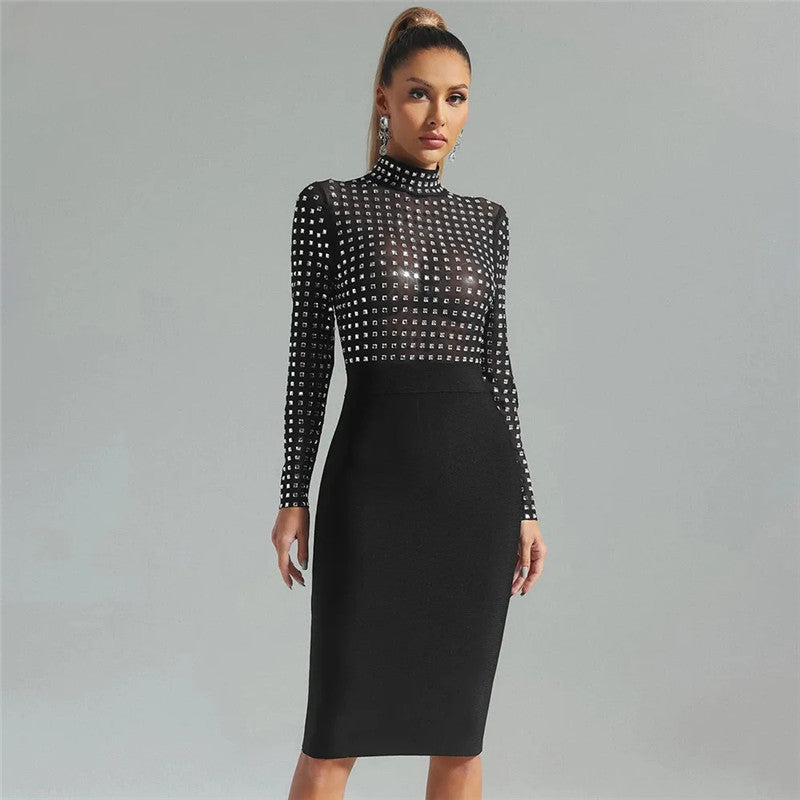 Woman wearing a black long-sleeved mock neck dress with sheer rhinestone-embellished top and a black pencil skirt, posing against a grey background.