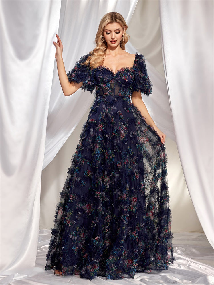 The gown features a vibrant, multicolored floral print scattered across the navy blue tulle fabric.