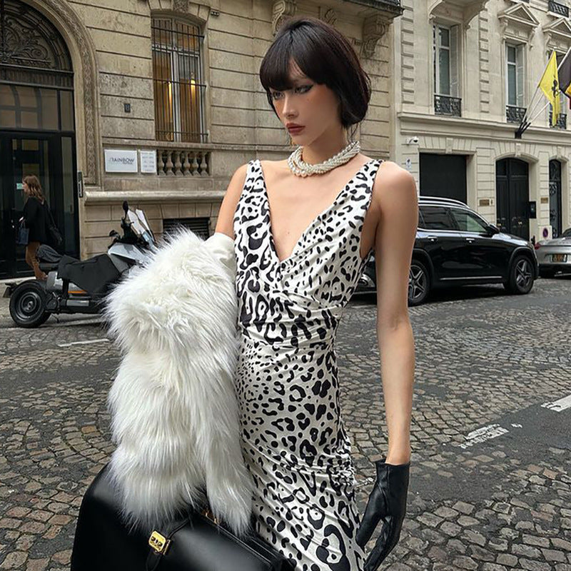 Close-up of a woman in a leopard print dress and faux fur coat, holding a black handbag.
