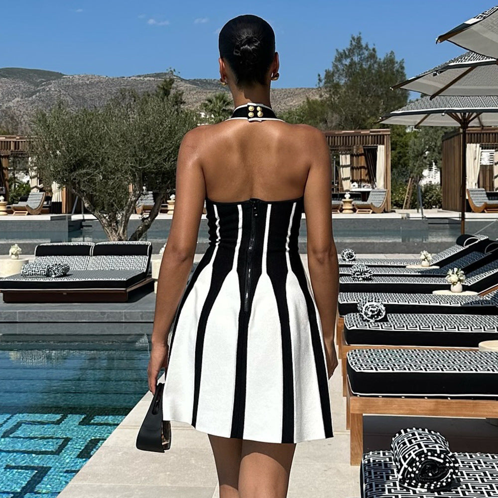 Rear view of a woman wearing a black and white halter neck fit and flare dress with a striped pattern and zip closure.