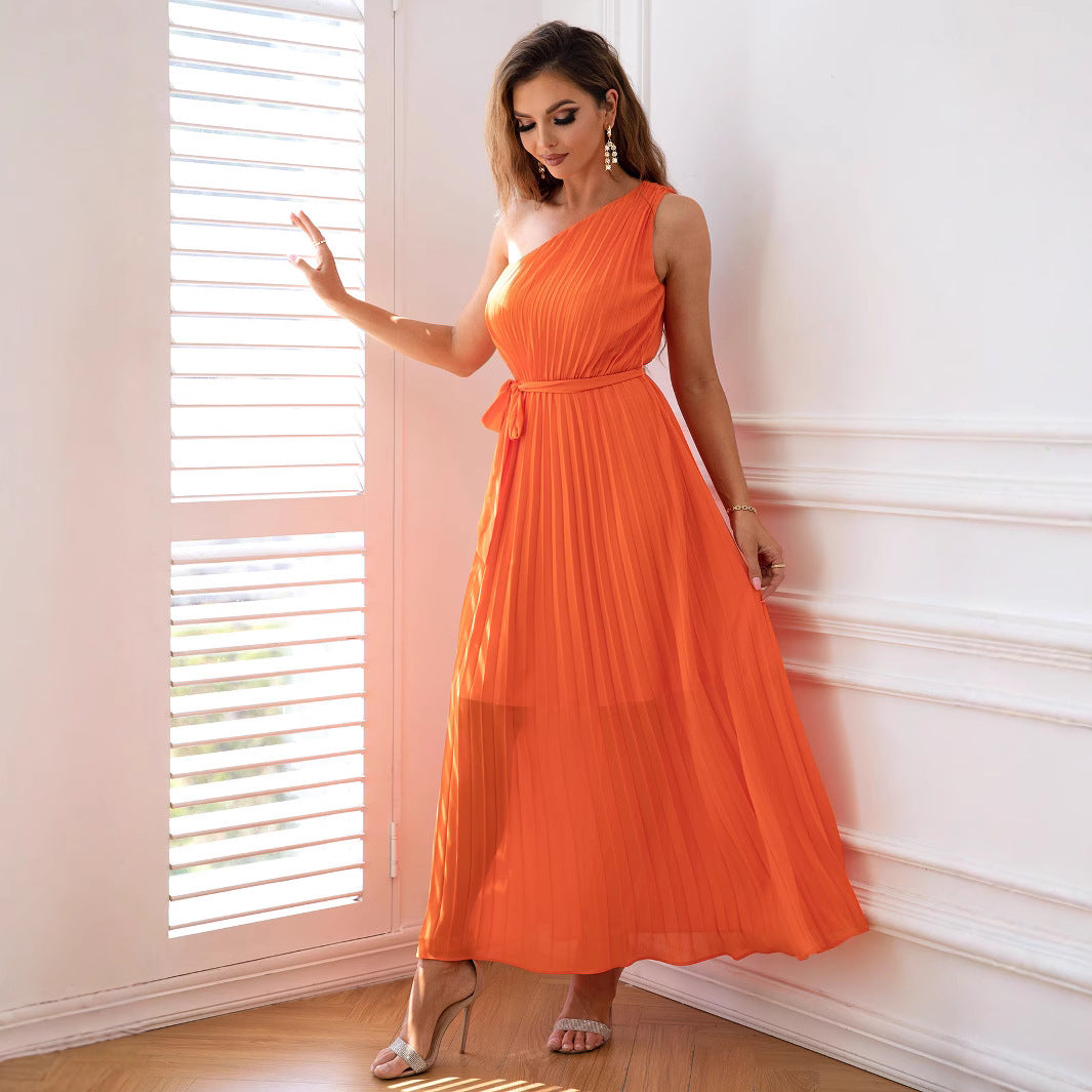 woman in an orange one-shoulder pleated maxi dress
